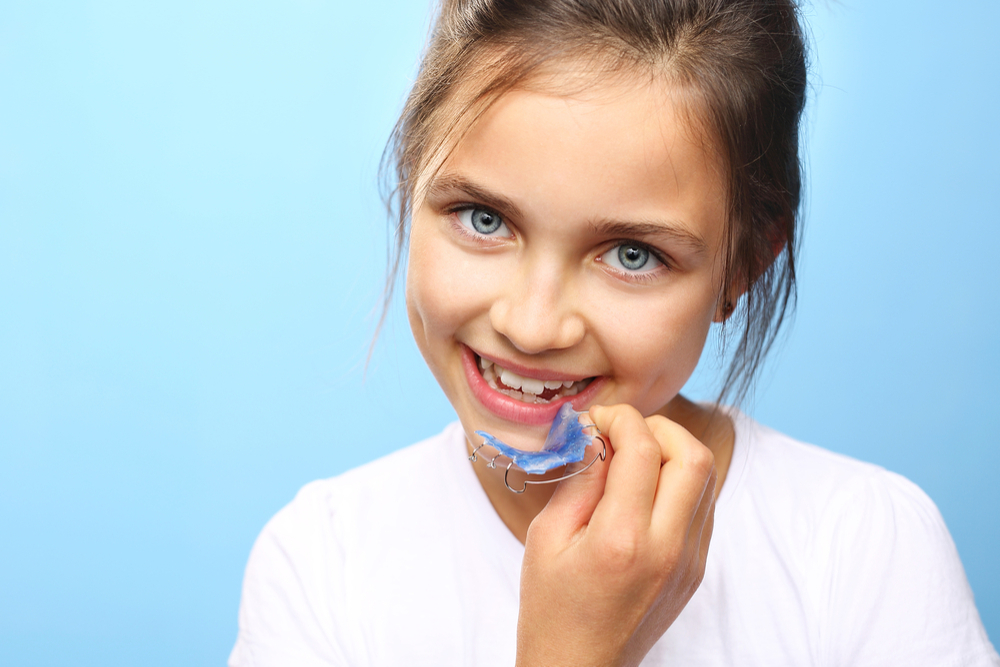 image of young girl putting in retainer